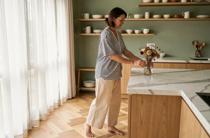 Femme portant un tee-shirt rayé noué avec un pantalon en lin large dans un appartement moderne à la décoration épurée